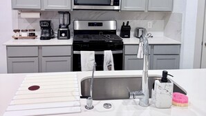 Una cucina moderna con mobili grigi, un forno a microonde in acciaio inossidabile, una macchina da caffè e un lavello con rubinetto in marmo.