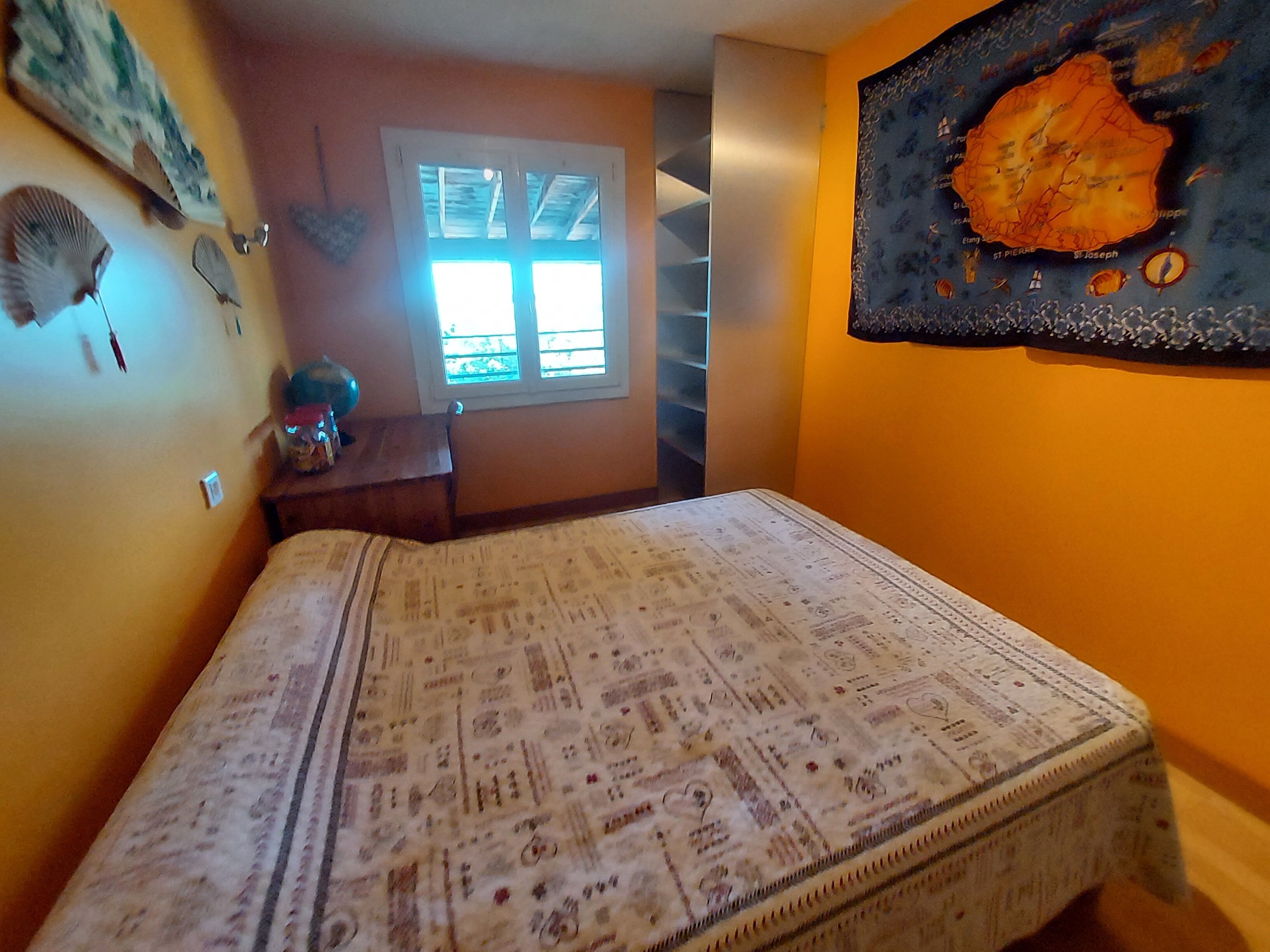 A bedroom with a bed, a window, and a wall map.