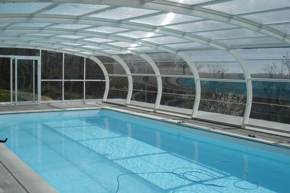 Une piscine dotée d’une enceinte en verre, avec une eau cristalline et une vue sur le paysage environnant.