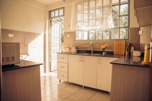 Eine moderne Küche mit Holzschränken, einer schwarzen Arbeitsplatte, einem Spülbecken und einem Fenster mit Blick auf Bäume.