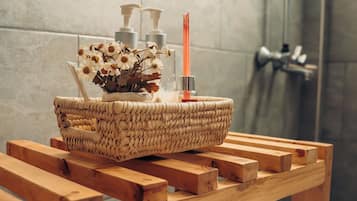 Ein Badezimmer mit einer hölzernen Sitzbank, einem gewebten Korb mit Toilettenartikeln und einem Handtuch.