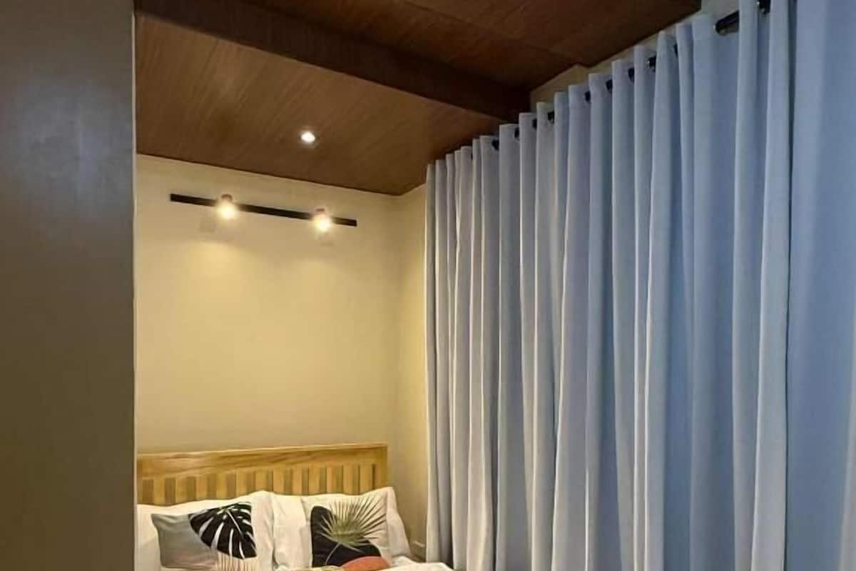 A bed with a wooden headboard, white bedding, and a bedside table with a tray.