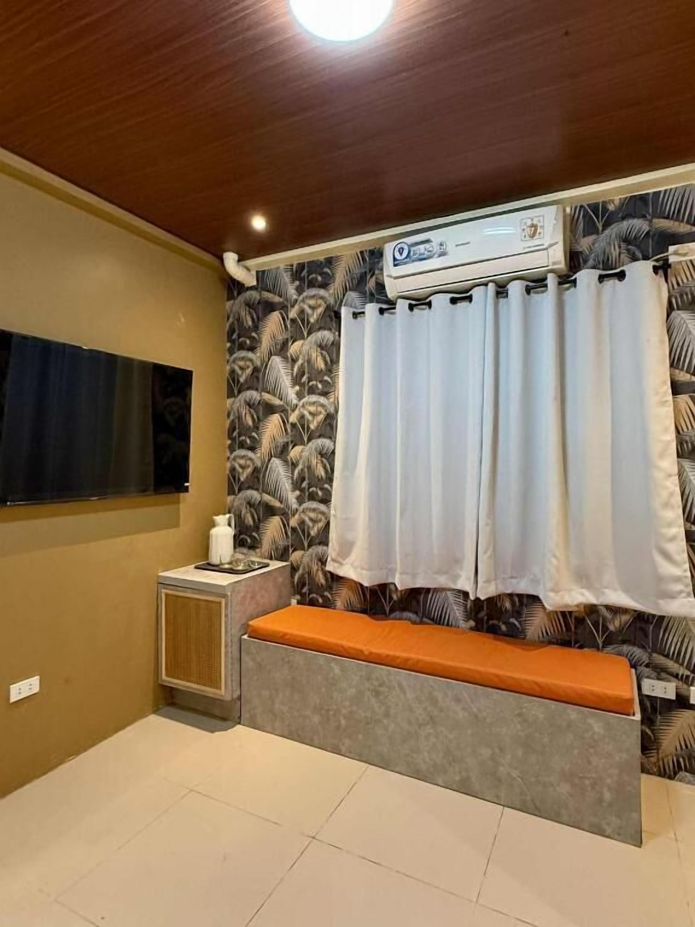 A room with a bench, an air conditioning unit, a window, and patterned wallpaper.