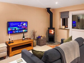 A living room with a television, a fireplace, a sofa, and a small table. - The Cartshed - UK50426 (Malton)