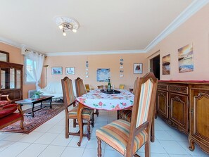 A dining area with a round table, chairs, and a chandelier. - Hotel de Ville by Interhome (Perros Guirec)