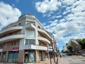 A multi-story building with balconies, a storefront labeled 'SQUARE HABITAT,' and a street with cars and pedestrians. - Hotel de Ville by Interhome (Perros Guirec)