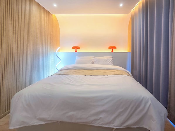 A modern hotel room with a bed, two bedside lamps, and a wooden panel wall. - Damyang DAUM Spa Village (Damyang)