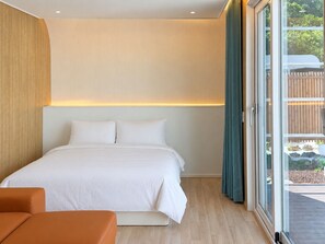 A modern bedroom with a large bed, a wooden headboard, and a view of the outdoors through a glass door. - Damyang DAUM Spa Village (Damyang)