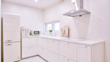 A modern kitchen with white cabinetry, a built-in microwave, and a stainless steel range hood.