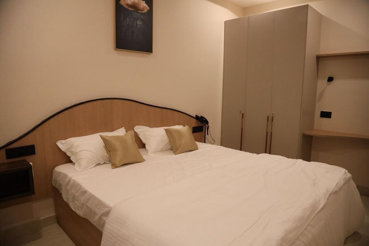 A bedroom with a bed, a nightstand, a wardrobe, and a painting on the wall.