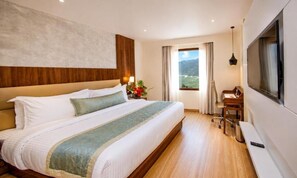 Habitación de hotel con una cama grande, un escritorio, una silla, un televisor y una ventana con vistas.