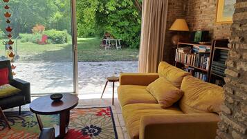 Ein gemütliches Wohnzimmer mit einem gelben Sofa, einem kleinen runden Tisch und einem Bücherregal.