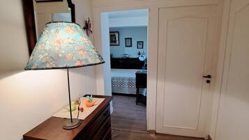 A hallway with a wooden dresser, a lamp, and a door leading to another room.