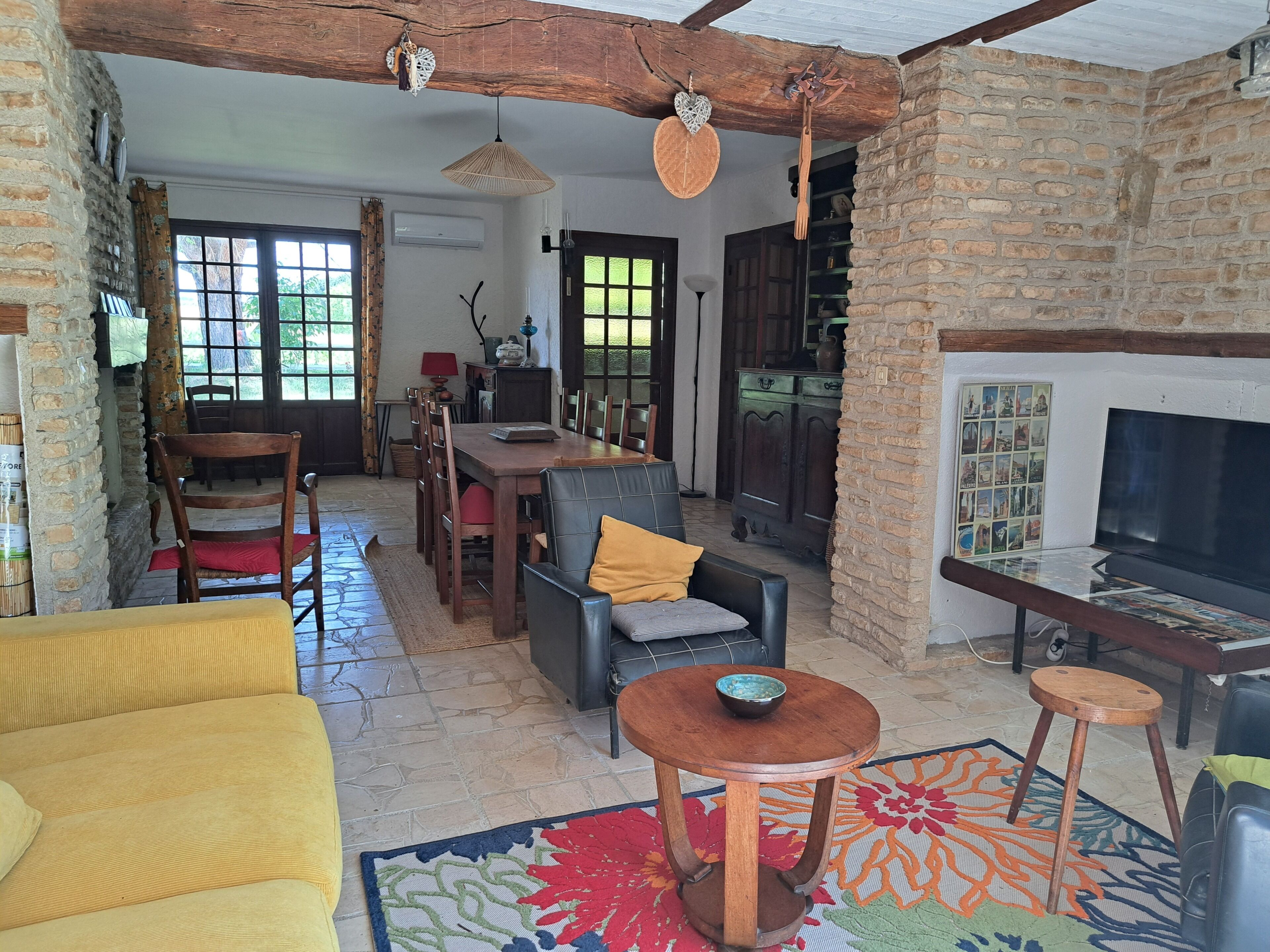 Un salon chaleureux avec une cheminée, un coin repas et un espace détente comprenant un canapé et des fauteuils.