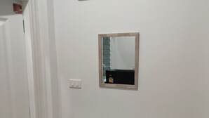 A room with a white door, a wall-mounted mirror, and a shelf. - ROW HOUSE WITH PRIVATE POOL, Corner Townhouse with Private Pool (หัวหิน)