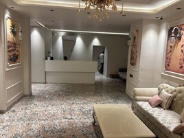 Um hall de hotel com uma recepção, um sofá, um banco e um candelabro.