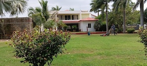 A residential area with a house, a lawn, and a person mowing the lawn. - Asiatic Pride Resort (Dhari)