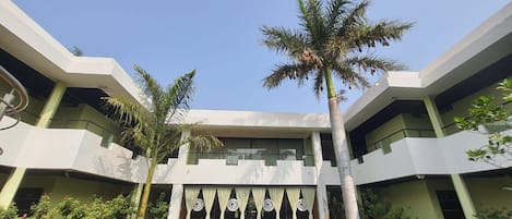 Un edificio moderno con fachada simétrica, varios balcones y una entrada central con una palmera.