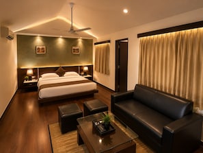 Quarto de hotel moderno com uma cama grande, um sofá de couro, uma mesa de centro e um ventilador de teto.