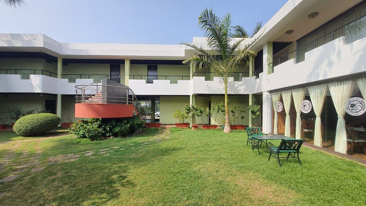 A courtyard with a central staircase, a palm tree, and a seating area with tables and chairs.