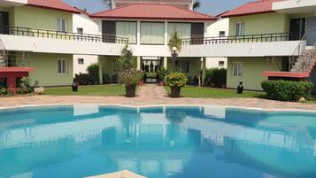 Um hotel com piscina, várias varandas e um jardim bem cuidado.