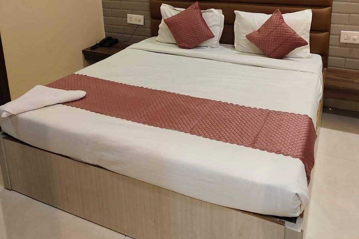 Habitación de hotel con cama, mesita de noche, aire acondicionado de pared y pared de paneles de madera.