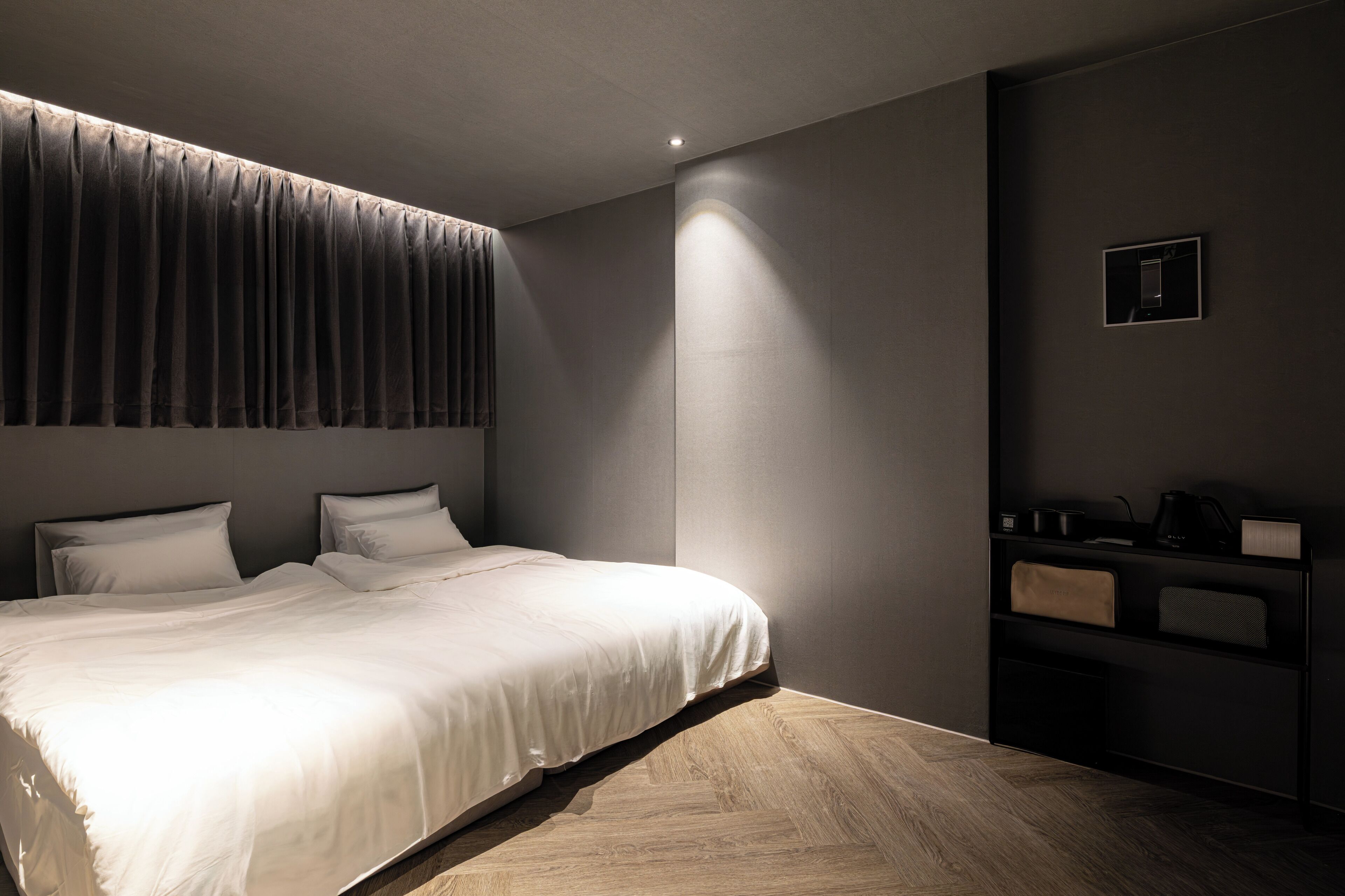 Een moderne hotelkamer met een groot bed, nachtkastje, inbouwkast en wandlamp.