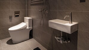 Uma casa de banho moderna com sanita, chuveiro e lavatório.