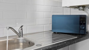 A kitchen with a stainless steel sink, a blue toaster, and a white tiled backsplash. - Cheshire Gold: Beautiful studio apartment near  Warrington town centre (Warrington)