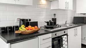 A modern kitchen with white cabinets, a black countertop, and a variety of kitchen appliances. - Cheshire Gold: Beautiful studio apartment near  Warrington town centre (Warrington)