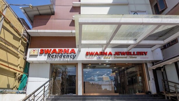 Um edifício com uma placa indicando 'Swarna Residency' e 'Swarna Jewellery' no andar térreo.