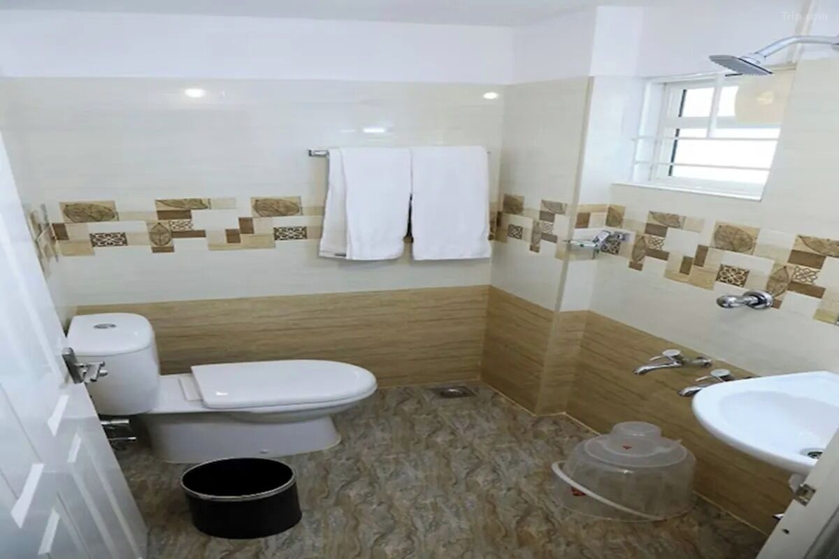 Une salle de bain comprenant des toilettes, un bidet et un lavabo. Il y a une fenêtre au-dessus du lavabo et un porte-serviettes avec deux serviettes.