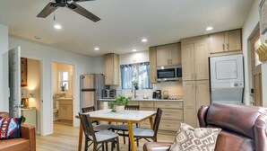 Eine moderne Küche mit Holzausstattung, einem Esstisch mit Stühlen, einem braunen Ledersofa und einem Deckenventilator.