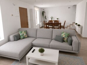 A modern living room with a grey sectional sofa, a white coffee table, and a dining area with wooden chairs and a white table.