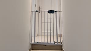 En smal trappa leder upp till en vit dörr med ett metallgaller högst upp.