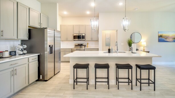 A modern kitchen with stainless steel appliances, a large island with bar stools, and pendant lighting. - Palm Coast Escape: Bike Trails & Beach Days! (Palm Coast)