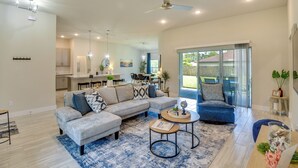 A spacious living area with a large sofa, a coffee table, and a dining area in the background. - Palm Coast Escape: Bike Trails & Beach Days! (Palm Coast)