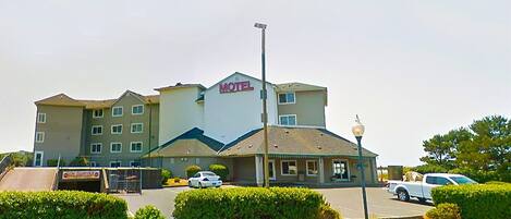 A motel with a sign, a parking lot, and a street lamp.