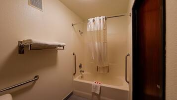 Une salle de bain équipée d’une baignoire, d’un rideau de douche, d’un porte-serviettes et d’une barre d’appui.