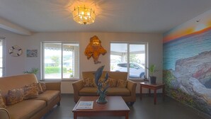 A hotel lobby with a sofa, a coffee table, a wall-mounted sculpture, and a mural of a coastal scene.