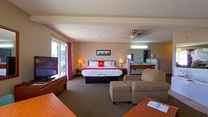 A hotel room with a bed, television, desk, chair, and a bathroom with a bathtub.