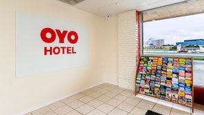 A hotel interior with a prominent 'OYO HOTEL' sign, a bulletin board with various pamphlets, and a view of buildings outside through a window. - 2 King Bed Non Smoking | Antonio Lackland (San-Antonio)