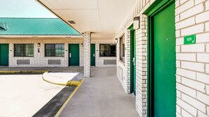 A building with a brick facade, green doors, and a number sign '109' on the wall.