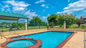 A rectangular swimming pool with a brick border, a covered area, and a fenced perimeter.