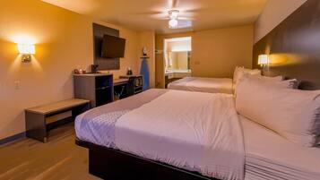 Ein Hotelzimmer mit Bett, Nachttisch, Schreibtisch, Stuhl und Deckenventilator.
