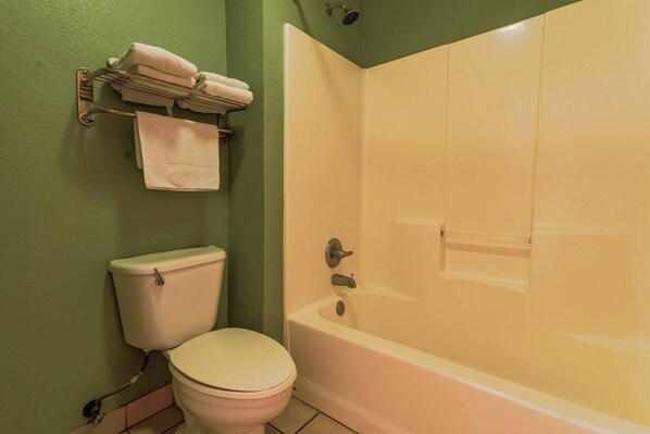 A bathroom with a toilet, a bathtub, and a towel rack with towels.