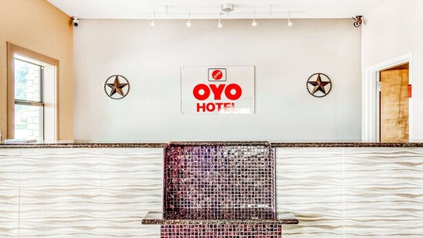 A reception area with a tiled counter, a sign reading 'OYO HOTEL', and two star decorations on the wall.