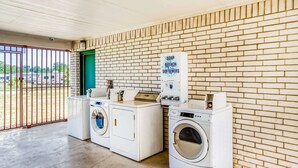 A laundry area with three washing machines, a soap and bleach softener dispenser, and a green door.