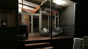 Una casa moderna con un porche cubierto, una puerta corrediza de vidrio y un pequeño espacio para sentarse al aire libre.
