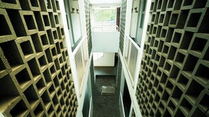 A narrow corridor with a grid-like pattern on the walls, leading to a window at the end. - Rehat at Alamanda 7 Syariah Guest House (Bandung)